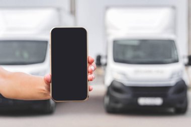 Bir kadının elinde telefon. Kamyonların arka planına karşı. Lojistik kavramı