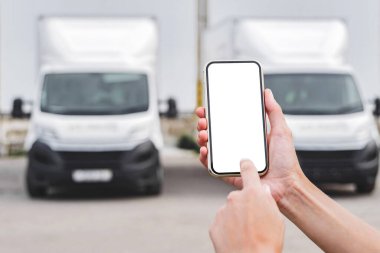 Kadın ellerinde akıllı telefon modeliyle. Kamyonların arka planına karşı. Lojistik kavramı