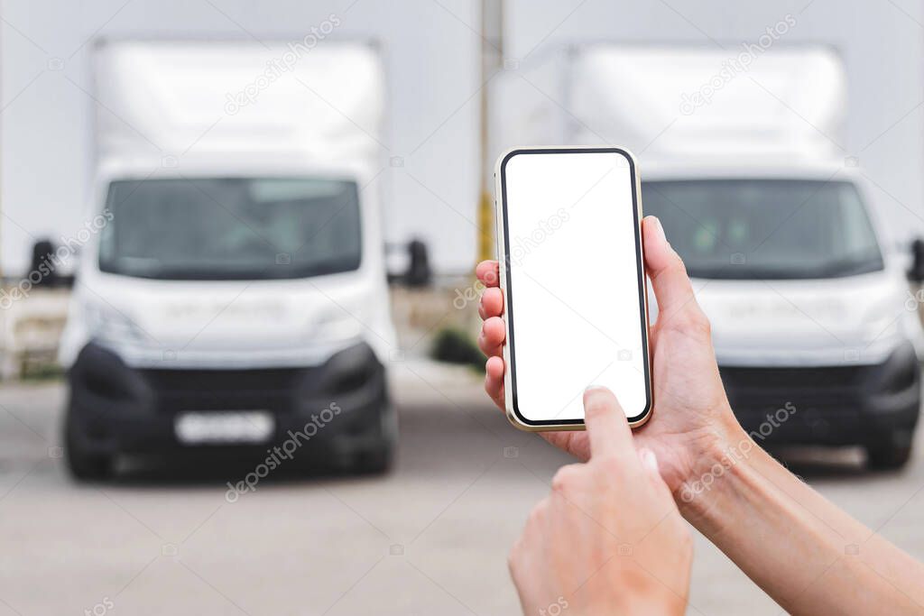 Smartphone mockup in female hands. Against the backdrop of trucks. Logistics concept