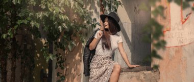 Ağaçların, eski binaların arasında yürüyen bir kız.