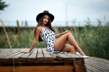 Nehrin kenarında yürüyen, köprüde oturan, kitap okuyan bir kız.