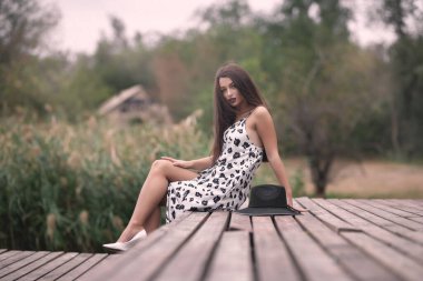 Nehrin kenarında yürüyen, köprüde oturan, kitap okuyan bir kız.