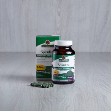 Kamianets-Podilskyi, Ukrayna, 7 Mart 2022, Koyu yeşil bir ilaç şişesi. Ön taraftaki küçük yeşil kapsüller. Doğanın cevap paketi spirulina.. 