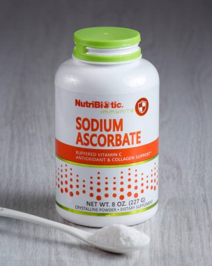 Kamianets-Podilskyi, Ukrayna, 7 Mart 2022: Hafif bir arkaplanda beyaz sodyum askorbat paketi. Önünde beyaz toz olan beyaz kaşık. Bir kaşıkta C vitamini tozu. 