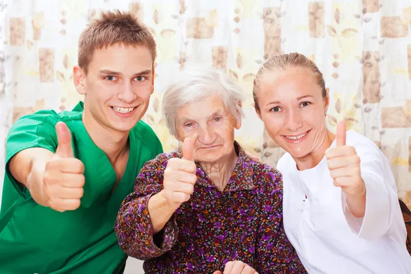 Elderly woman with the young doctors — Stock Photo, Image