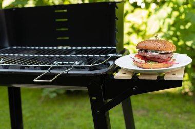 Ev yapımı lezzetli çizburger arka bahçede mangalda pişiriliyor.