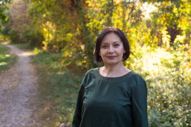 Dışarıda poz veren orta yaşlı güzel bir kadının portresi.