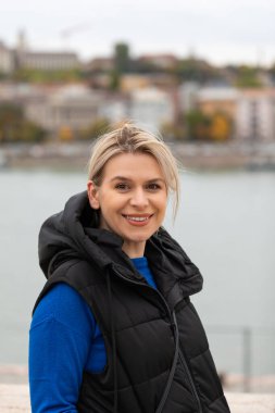 Kameraya gülümseyen güzel bir genç kadının portresi, rüzgar saçlarını dalgalandırıyor.