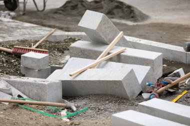 Üniformalı bir adam inşaat sahasına kaldırım döşüyor.