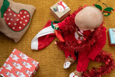 Noel hediyesi kutusuyla oynayan mutlu bir bebek resmi.