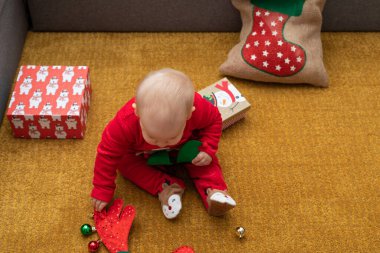 Noel hediyesi kutusuyla oynayan mutlu bir bebek resmi.