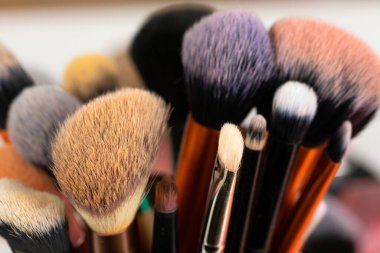 Beyaz arka plandaki temiz ve kirli makyaj fırçalarının ve aksesuarların resmini kapat