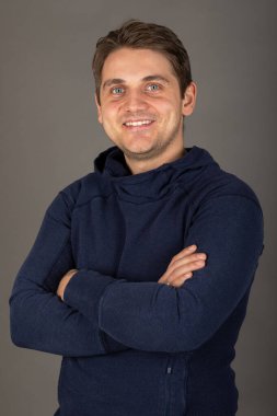 Gri arkaplan önünde kameraya bakan mavi gözlü yakışıklı sarışın bir adamın portresi.  