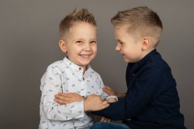 Gri arka planda birbirine sarılan iki kardeş.