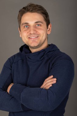 Gri arkaplan önünde kameraya bakan mavi gözlü yakışıklı sarışın bir adamın portresi.  