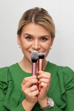 Genç ve güzel bir kadın makyajını fırçayla yapıyor.