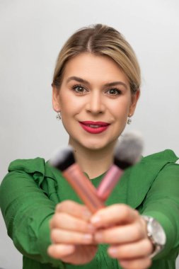 Genç ve güzel bir kadın makyajını fırçayla yapıyor.