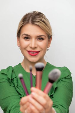 Genç ve güzel bir kadın makyajını fırçayla yapıyor.