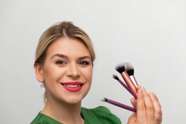 Genç ve güzel bir kadın makyajını fırçayla yapıyor.