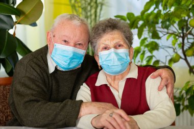 Evde maske takan yaşlı bir çift, kendilerini izole ediyorlar.