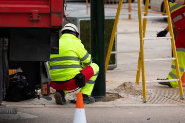 Şehir caddesinde trafik lambasını tamir eden iki elektrikçi.