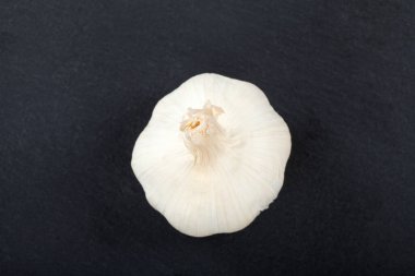 Top view of a garlic bulb on a black cutting board