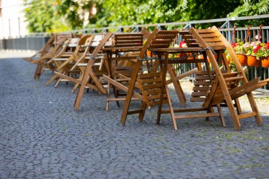 Empty folded  wooden  chairs and tables at coffee and restaurant terrace 