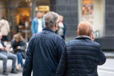 Şehirde yürüyen yaşlı bir çiftin fotoğrafı. 