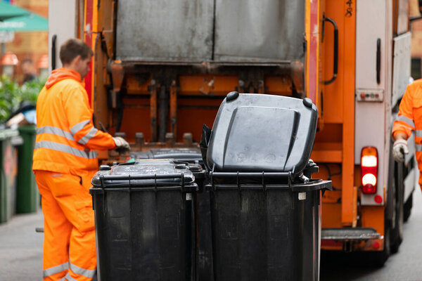 Изображение мусоровоза, собирающего мусор в большом городе 