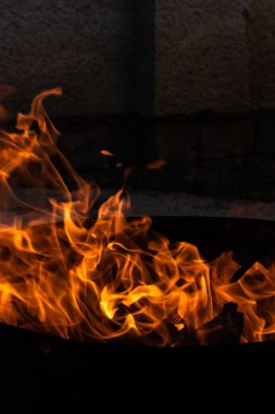 Yaz zamanı aktivitesi, açık havada yanan küçük şenlik ateşi, karanlıkta turuncu alevleri yakın çekim.