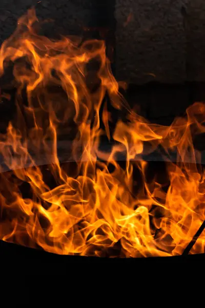 Yaz zamanı aktivitesi, açık havada yanan küçük şenlik ateşi, karanlıkta turuncu alevleri yakın çekim.