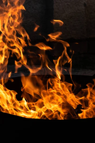 Yaz zamanı aktivitesi, açık havada yanan küçük şenlik ateşi, karanlıkta turuncu alevleri yakın çekim.