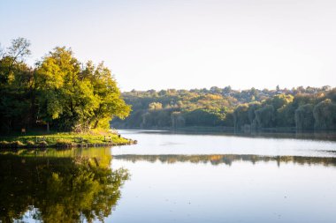 Pecs, Macaristan, Avrupa yakınlarındaki güzel bir gölün sularına yansıyan düşen ağaçların ideolojik manzarası