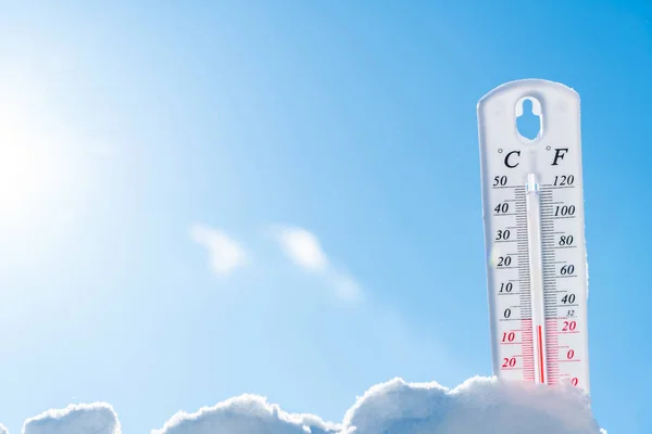 Karda termometre. İklim, hava, hava durumu. Dışarıdaki sıcaklıklar. Kardaki termometre sıfırın altında sıcaklık gösteriyor. Düşük sıcaklıklar Celsius 'ta ve karlı havada fahrenhayt' ta
