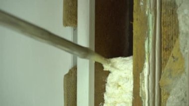 İnşaat köpüğü kullan. Köpük montajında usta, kapı pervazını tamir eder. Usta inşaat köpüğü kullanıyor. Kurucu kapıyı köpükle doldurur. Poliüretan.
