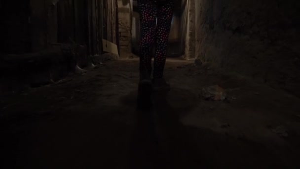 懐中電灯を持った少女が暗い地下を歩いている 子供は古いダンジョンで迷子になった 少女は爆弾倉の中を歩く カタコンベの子供だ 危険なクローゼットだ 迷子の女の子 — ストック動画