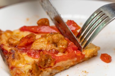Yakın plan bir tabakta bir dilim pizza. Çatal ve bıçakla pizza ye. Öğle yemeğinde çatal bıçak kullan. Sulu bir dilim pizza. İtalyan mutfağı.