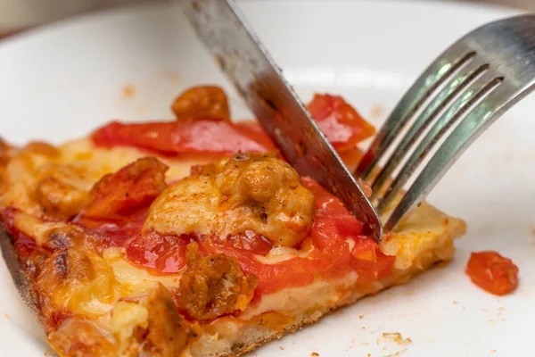 Yakın plan bir tabakta bir dilim pizza. Çatal ve bıçakla pizza ye. Öğle yemeğinde çatal bıçak kullan. Sulu bir dilim pizza. İtalyan mutfağı.