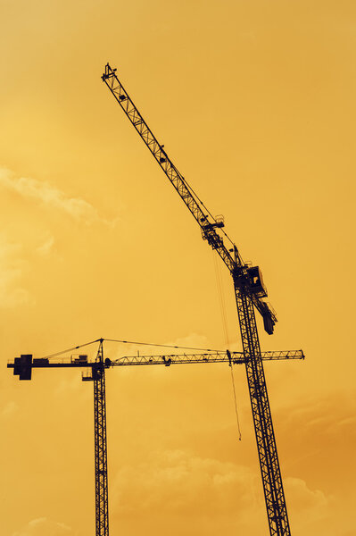 Two cranes at construction site silhouette.