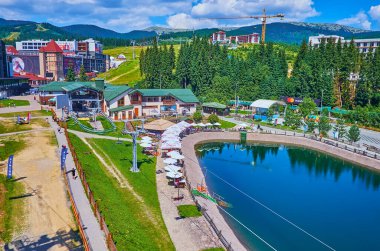 BUKOVEL, UKRAINE - 25 Temmuz 2021: 25 Temmuz 'da Bukovel' de Bukovel Dağı yamacında yer alan Trout Pond 'un, turistik kafelerin ve modern kır evlerinin havadan görünüşü