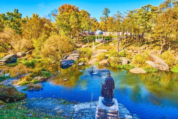 Скульптура княгини Ольги, стоящей на берегу реки Уж, наблюдает за красивым осенним Древлианским парком в Коростене, Украина
