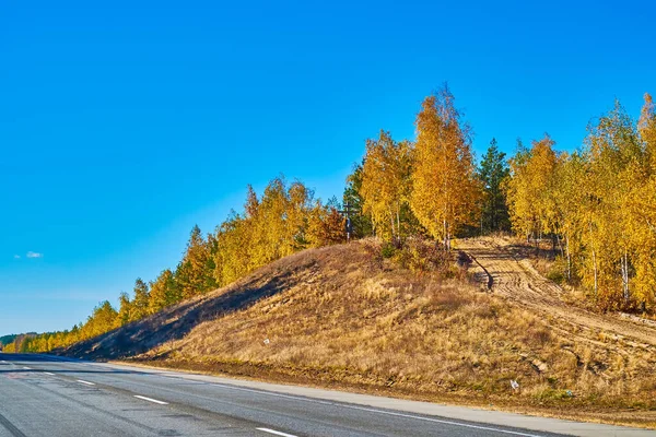 乌克兰城市间公路边缘的小山 与秋天的森林和蜿蜒的土路相连 — 图库照片