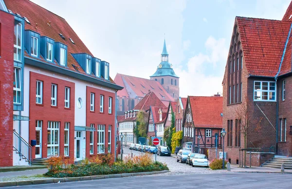 小さな住宅中世の家とドイツのルネブルクの背景に聖マイケル教会の屋根と鐘楼と広い通り — ストック写真