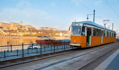 Belgrad Rıhtımı 'nda Tuna Nehri ve Buda Şatosu' na karşı geçen sarı tramvay arka planda Budapeşte, Macaristan 'ın başkenti Budapeşte' de görülüyor.