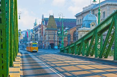 Manzaralı sarı tramvay Fovam Meydanı üzerinden Budapeşte, Macaristan 'daki Liberty Köprüsü' ne gidiyor.