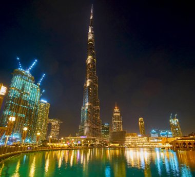 DUBAI, BAE - 3 Mart 2020: Burj Halife Kulesi 'nin gece aydınlatması ve Burj Gölü' nün yüzeyinde 3 Mart 'ta Dubai' de yansıyan gökyüzü manzarası