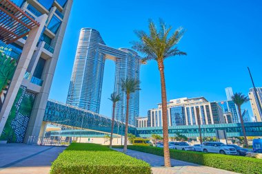 DUBAI, BAE - 3 Mart 2020: Şeyh Muhammed Bin Rashid Bulvarı boyunca uzanan güneşli palmiye geçidi, Dubai şehir merkezinin modern cam gökdelen adresi Sky View ile 3 Mart 'ta Dubai' de hizalanmıştır.