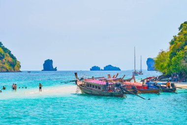 AO NANG, THAILAND - APRIL 26, 2019: The longtail boats on shallow waters of Andaman sea at Koh Tup and Koh Mor Islands, connected with narrow sand spit, on April 26 in Ao Nang clipart