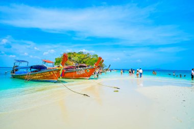 AO NANG, THAILAND - 26 Nisan 2019: Turistler, 26 Nisan 'da Ao Nang' da, alçak gelgit sırasında Koh Mor ve Koh Tup adalarının kumları üzerinde uzun kuyruklu teknelerde yürürler.
