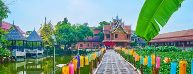 Wat Jedlin tapınağının bahçesi nilüfer çiçekleri, renkli fenerli eski bambu köprüsü, küçük yaz çadırları ve tapınak binaları, Chiang Mai, Tayland ile kaplı manzaralı göle bakıyor.